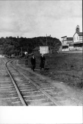 Two women walking along railroad tracks