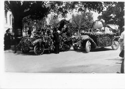 Car with a doll on the hood and a car decorated as a flower basket