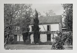 Unidentified two-story home with a grape arbor over a stone or concrete porch running the width of the house and enclosed by low stone walls, 1960s or 1970s