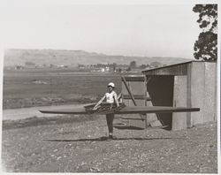 View George P McNear, Jr as he removes his scull boat from the boat house on the Petaluma River, Petaluma, California, about 1910