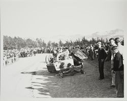 Crowd examining a racing car wreckage