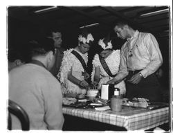 Two girls wearing chicken costumes lighting candles on a cake, Petaluma, California, about 1956