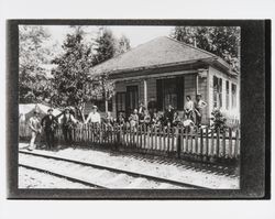 Men in front of a house next to the railroad tracks