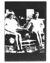 Two girls dressed as chickens sitting on the hood of a car, Petaluma, California, 1954