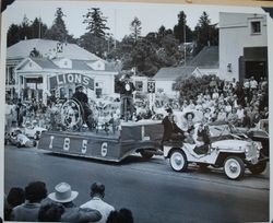 Henry Martin driving the Sebastopol Lions Club float on South Main Street past the Sebastopol Post Office in the Apple Blossom Parade, about 1956, with Edna Martin in the front seat and Edgar Herring and Billie Herring in back (Sebastopol Lions Club scrapbook photo)