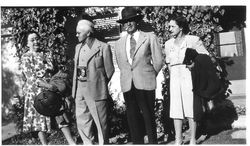 Charles R. and Eva Myers and an unidentified couple standing outside a vine-covered house or building in 1945