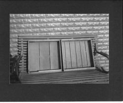 Two fruit drying trays on a wooden bench against a brick wall or building
