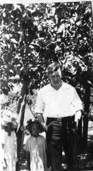 Ludford W. Elvy under an apple tree with his daughters Harriet and Wilma