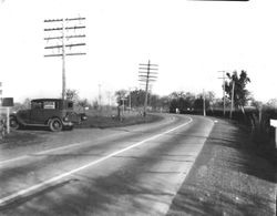 1930s car with sign in the window for William Borba parked on the side of Gravenstein Highway at McKay's Corner, south of Sebastopol, California, 1930s
