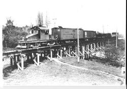 String of Petaluma and Santa Rosa Electric Railway (P&SR) boxcars including a Pacific Fruit Express car being pulled by an engine across a trestle