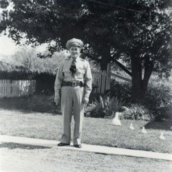 Sebastopol Police Officer Lemuel "Shorty" Plumley in uniform standing in a yard