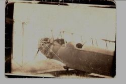 Fuselage of Sam Huck's Jenny biplane with an unidentified man in the back cockpit, wearing a leather helmet