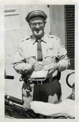 Sebastopol Police Officer Lemuel "Shorty" Plumley writing on a notepad next to his motorcycle, about 1960