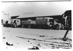 Pacific Fruit Exchange building and trucks loaded with boxes of apples, 1930s