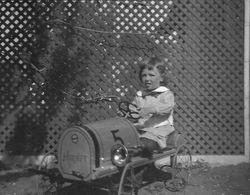 Child in small toy car, about 1920s