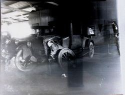 Two vintage 1920s cars in a repair shop