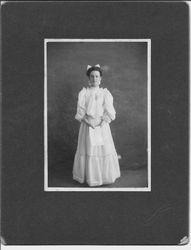 Unidentified young girl in long dress holding a paper, photographed in the 1880s or 1890s