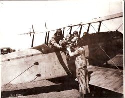 Pilot Sam Huck Sr. in his Curtiss JN-4 "Jenny" biplane, receiving flowers from "Tee" McMinamin (Rose), writer for the San Francisco Examiner, at the May 16, 1928 Air Show