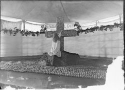 Gravenstein Apple Show exhibit, about 1915 in Sebastopol, showing display of manikin girl at the foot of a cross made of apples