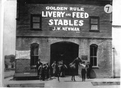 Group of men stand in entryway of brick building of Golden Rule Livery Stable that was located on South Main and Burnett Streets Sebastopol, in 1890