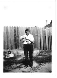 Harry White, at age 13 years, holding a sack by a wooden fence