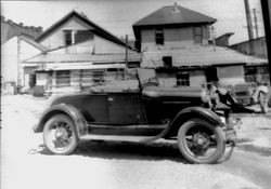 1930s convertible car standing in front of several buildings