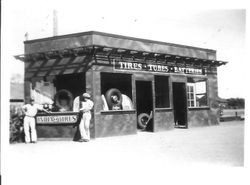 Small service shop for tires, tubes and batteries and an India Tires sign on the side of the building, 1932