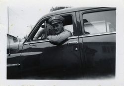 Sebastopol Police Officer Lemuel "Shorty" Plumley in uniform in a dark car looking out the window at the photographer