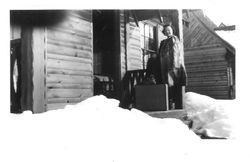 Bunni Cornelia E. Myers standing in a fur coat with luggage at the front door of cabin surround by snow, 1941