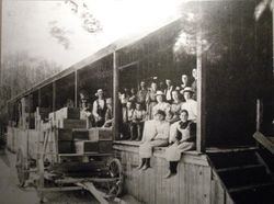 Unidentified apple processing building with men, women and children workers on the loading dock, early 1900s