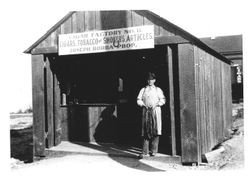 Joseph Borba stands at the entrance to his tobacco factory holding tobacco leaves