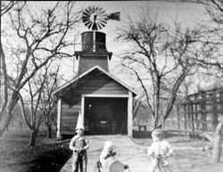 Three unidentified children playing in the driveway of a garage, 1930s