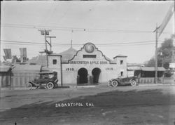 Gravenstein Apple Show exhibit, about 1915 in Sebastopol, showing building on Main Street that served as entrance to and large tent behind that housed the Gravenstein Apple Show