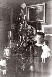 Two young girls standing in front of a Christmas tree, about 1909