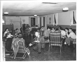Robert Brabec talking with two unidentified women at a racket club, about 1950s