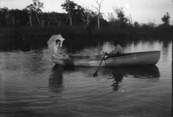 Two unidentified people in a rowboat, the lady holds a parasol and the man is rowing on Lake Jonive