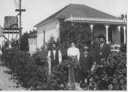 Small Queen Anne cottage with family in front yard about 1900