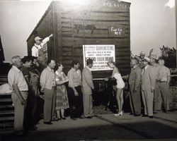 Ribbon cutting ceremony in front of a railroad car, "First Car No. 1," carrying Gravenstein apples from Sebastopol and the Sebastopol Apple Growers Union, 1940s or 1950s