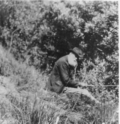 James (Jim) Furlong seated by water fishing at age 74, about 1915