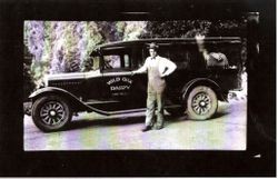 Unidentified man in front of a black delivery truck with "Wild Oak Dairy Camp Meeker" painted on driver's door