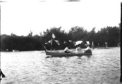 One man and two women in a boat with flags on Lake Jonive