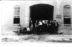 Group of men and boys standing in entryway of brick building of Golden Rule Livery that was located on South Main and Burnett Streets Sebastopol, in 1890