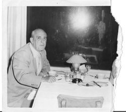 Dr. Bulman in a suit and tie is seated at a restaurant dining table
