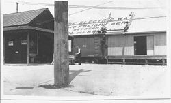 Workers painting a sign on the roof of the P&SR freight warehouse in Sebastopol, California advertising freight service between Sebastopol and San Francisco
