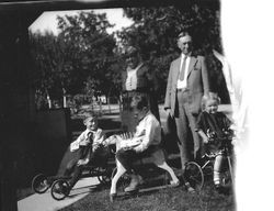 Two adults and three young children on tricycles, about 1930s