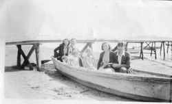 Two unidentified couples and two girls sit in a rowboat on the beach at Bodega Bay, about 1919