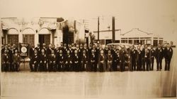 Large group of Japanese businessmen at a reunion of people from Mumamoto, Kaigaikyokai, Japan, standing in front of the original Sebastopol Chamber of Commerce mission-revival style building, about 1930