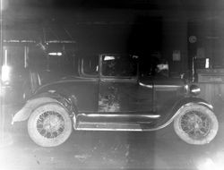 Vintage car sits in a repair garage, about 1930