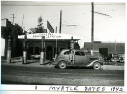 Myrtle Bates on the running board of an automobile parked in front of Crystal Service Station on North Main Street, Sebastopol, 1942