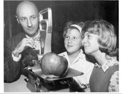 Kathleen Hallberg and her sister Donna Louise Hallberg (Marovich) watch as Gene Bologna, Sonoma County Sealer of Weights & Measures, weighs the large Hallberg Rome Beauty apple, November 22, 1963